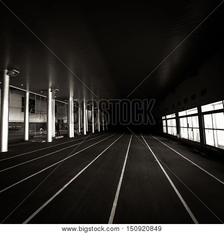 The lines of an indoor running track merge into the infinite darkness