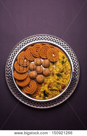 Plate full of indian festival food or diwali food or snacks like laddu, chivda, chakali or murukku, sev and shankar pale, sweet and salty snack food