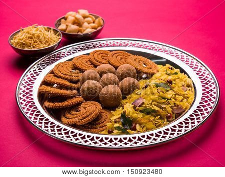 Plate full of indian festival food or diwali food or snacks like laddu, chivda, chakali or murukku, sev and shankar pale, sweet and salty snack food