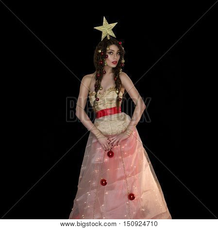 Beautiful young woman dressed like christmas tree with star on head. Studio shot on black background. Copy space. Sqaure composition.