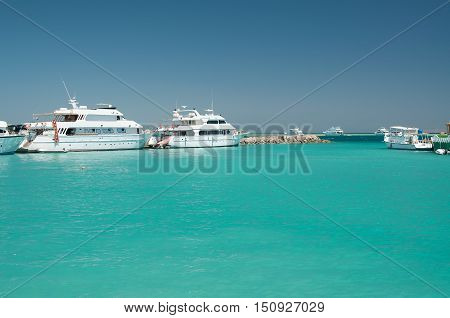 few white yachts near coral reef in the calm blue sea blue and cloudless sky