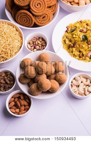 home made tasty Diwali food or Diwali snacks or Diwali sweets like rava laddu, chakli, sev,shankar pale and chivda or chiwada with dry fruits in white bowls, favourite indian diwali recipe