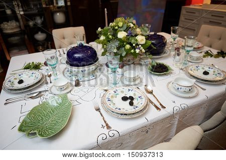 Decorated table ready for dinner. Beautifully decorated table set with flowers, candles, plates and serviettes for wedding or another event in the restaurant.