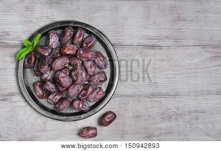 Side view of metal plate of Tunisian pitted dates mint. Dried dates on wooden white table top background. Top view.
