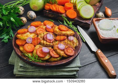 Vegetables ingredients for fried vegetable dishes in dough. Vegetables marrows white squashes carrots parsley lettuce dill tomato onions quail eggs flour Black wood background