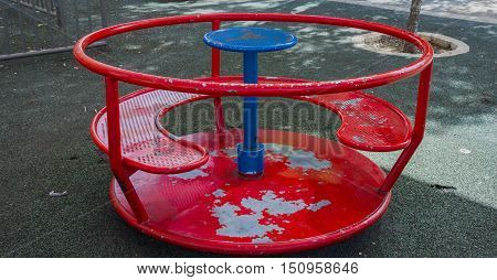 red children's carousel in the yard in the summer metal roundabout park