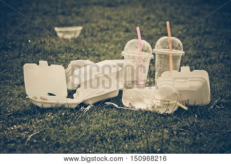 foam and plastic food container on grass field - environmental problems