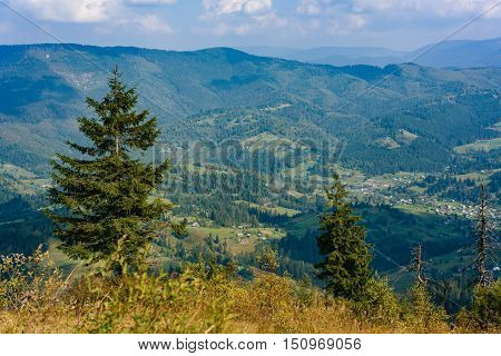 Top of the hill in Carpathian's. View to the village in mountains. Beautiful blue sky with clouds in the background. Summer time.