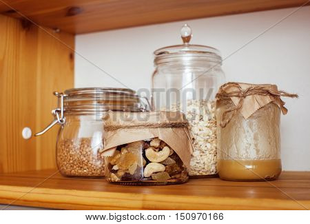 real comfort wooden kitchen with breakfast ingredients close up in glass, honey, oatmeal, milk, muesli