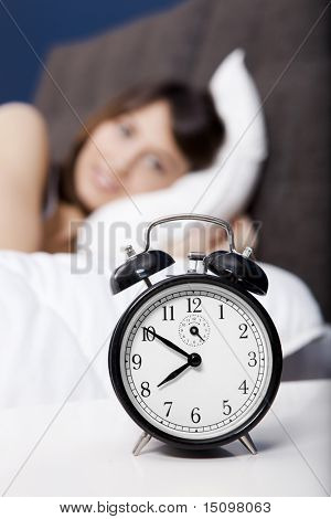 Porttrait de uma bela jovem, olhando para o relógio para dormir