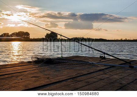 fishing utensils on a wooden platform on the pond