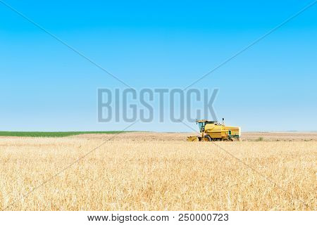Harvester In The Foreground On Rustic Background Working In The Field