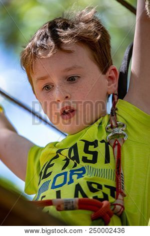 View Of Portrait Of A Handsome Boy On A Rope Park Among Trees. Children Summer Activities.