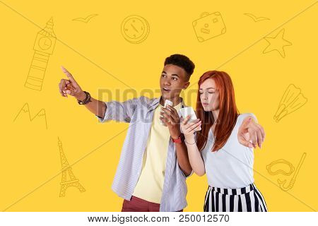 This Way. Young Active Couple Traveling Abroad And Using Their Modern Smartphones While Choosing The