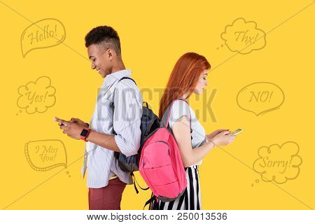 Chatting Online. Modern Teenagers Standing Back To Back And Looking At Eth Screens Of Their Modern S