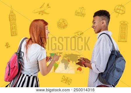 Map Of The World. Positive Friendly Students Smiling To Each Other While Holding The Map Of The Worl