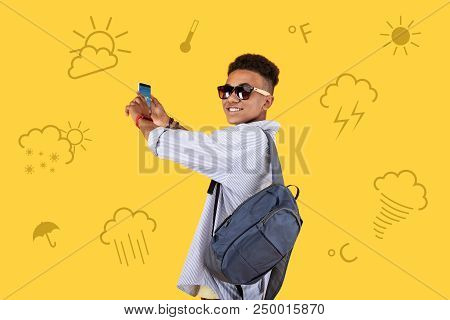 Good Weather. Attentive Positive Teenager Wearing Sunglasses And Standing With A Modern Gadget In Hi