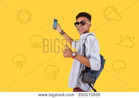 Perfect Weather. Optimistic Emotional Teenager Standing With A Modern Smartphone And Putting His Thu