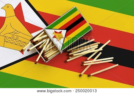 Zimbabwe Flag  Is Shown On An Open Matchbox, From Which Several Matches Fall And Lies On A Large Fla