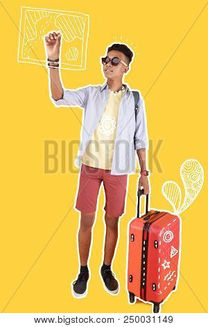 Drawing A Map. Handsome Relaxed Person Wearing Sunglasses And Carrying A Suitcase While Drawing A Ma