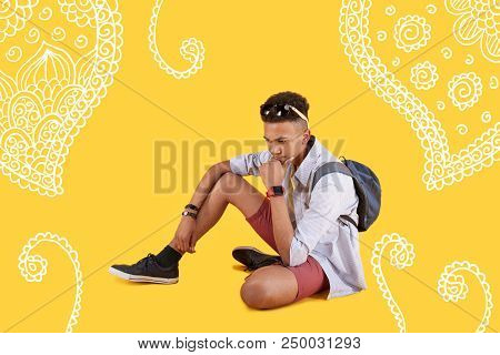 Thoughtful Boy. Calm Concentrated Boy Sitting On The Ground And Thoughtfully Touching His Chin While