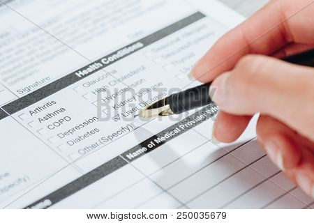 Cropped Image Of Woman Marking Liver Disease In Medical Questionary, World Hepatitis Day Concept