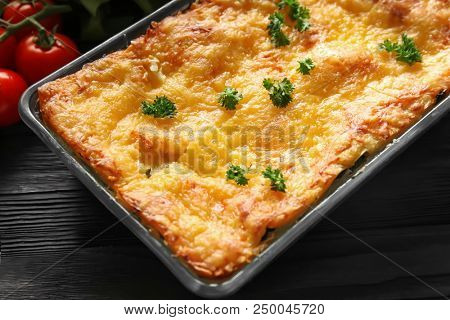 Baking tray with tasty spinach lasagna on wooden table