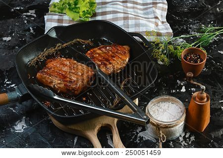 Grilled Pork Steaks On The Grill With Rosemary And Spices On Dark Wooden Background. Food Concept.