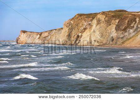 The colourful sandstone cliffs and choppy seas of Havre aux Maison, Magdalen Islands, Quebec Province, Canada.