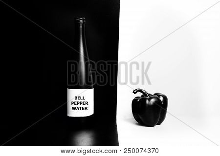 Black And Glossy Bell Pepper On A White Background And Unlabeled Black Mate Bottle On The Black Back