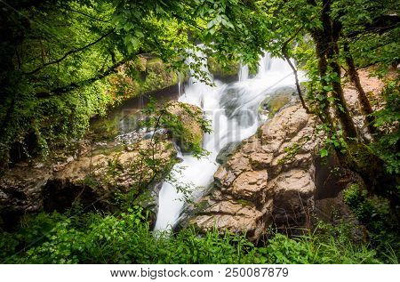 Amazing Forest Waterfall Flowing Into The Cold Mountain River With Large Stones. Martvili Canyon.