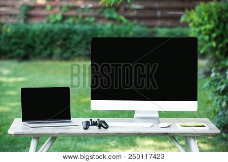 Selective Focus Of Joystick, Digital Tablet, Computer And Laptop With Blank Screens On Table Outdoor