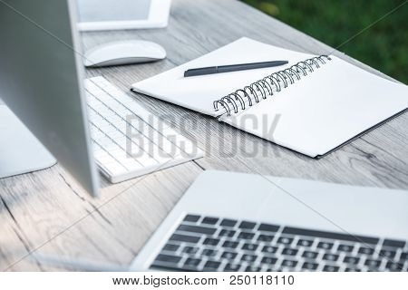 Selective Focus Of Empty Textbook With Pen, Laptop, Digital Tablet And Computer On Table Outdoors