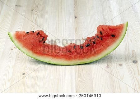 Cut And Bitten Red Juicy Watermelon Of A Large Size, The Berry Lies On A Wooden Table, Close-up