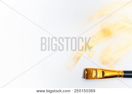 Beautiful Golden Strokes And A Brush Isolated On White Background.