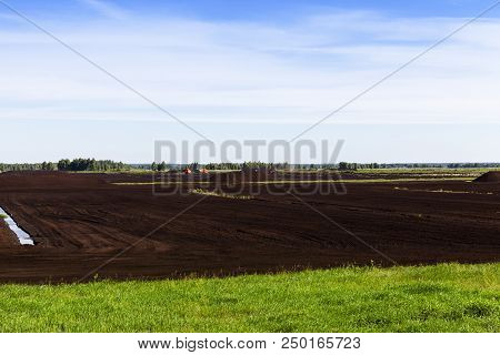 The Summer Landscape Of The Production Of Black Peat Used In Agriculture, Energy