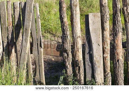 Part Of An Old Wooden Fence, Made Of Time-worn And Sun-blown Boards, Some Of Which Are Broken, A Clo