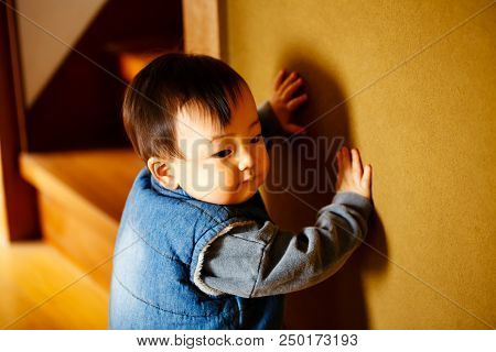 Beautiful Baby Boy Toddles In A Corridor At Japanese House. And Green Wall.