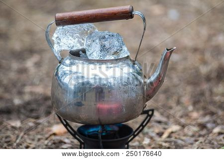 Travel Kettle With Ice On The Primus Fire. Gasoline Fuel.