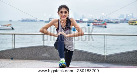 Sports Concept. Beautiful Girl Is Exercising On The Beach With Warm Up. Beautiful Girl Is Happy To E