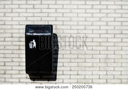 Black Rubbish On The Background Of A Light Brick Wall