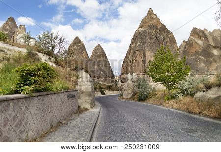 A Winding Road From Paving Stones Passes Near The Stone Cone Houses In The Ancient Rocks Of Goreme, 