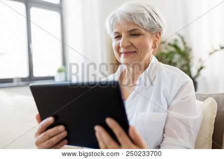 technology, age and people concept - happy senior woman with tablet pc computer at home