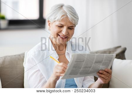age and people concept - senior woman marking newspaper ad at home