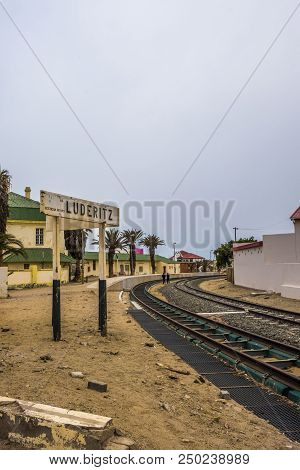 Luderitz, Namibia - March 23 2018: Two People In The Distance Walking Along Curve In Rail Tracks At 