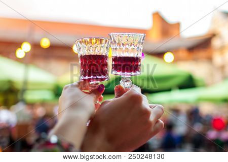 Couple Holding Glasses With Red Wine In Outdoor Restaurant. Man And Woman Toast In Cafe At Sunset. P