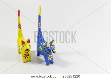 Perspective Close-up Shot Of Blue And Yellow Cat Figures Of Wooden Carved Nicknack