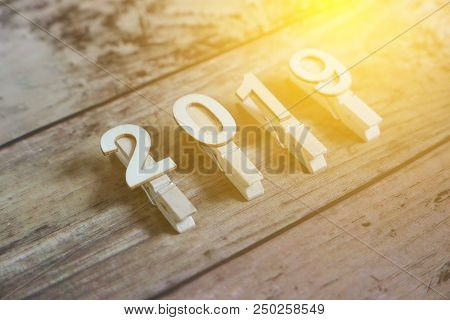 New Year 2019 Concept. Clothpin With Number 2019 On Wooden Background With Sun Flare.