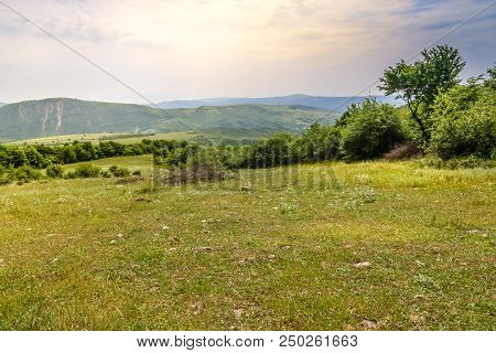 Green Meadow On The Background With Distant Mountains. Open Field With Green Grass. Landscape Photog