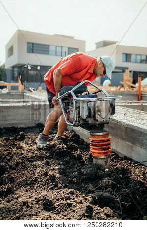 Worker On Construction Site Using Vibratory Compactor For Soil Compacting Or Earth Rammer